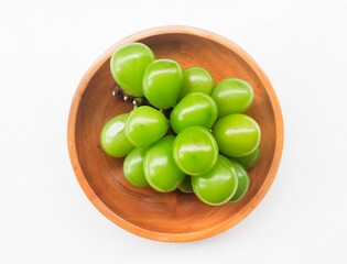 Green shine muscat grapes in a wooden plate on a white background. 