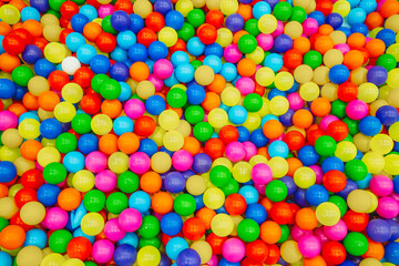 Colorful ball pit filled with vibrant plastic balls in various shades during a bright and sunny day at an indoor play center