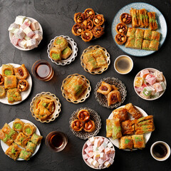 Assorted sweets and pastries served with coffee on a dark table, showcasing traditional desserts
