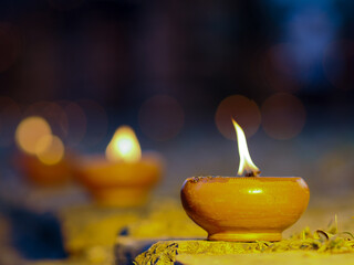 Burning candle in clay pot on wooden table with bokeh background