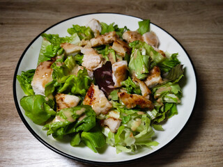A plate of fresh Caesar salad with grilled chicken, lettuce, and creamy dressing.