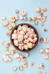 Top View of Makhana or Fox Nut in a Wooden Bowl Isolated on Light Blue Background with Copy Space in Vertical Orientation, Also Known as Lotus Seed Pop, Euryale Ferox or Gorgon Nut