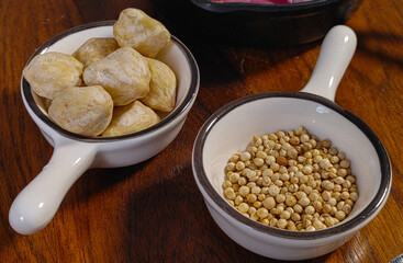 Top view of a wooden board with bowls containing shallots, garlic, coriander seeds, candlenuts, and red and green chili peppers. Ingredients for a flavorful Indonesian dish. Aromatic Indonesian Spice 