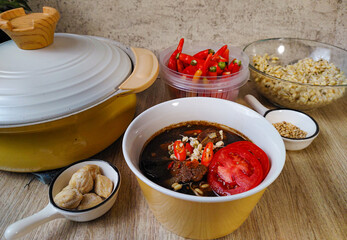  A bowl of Rawon, an Indonesian beef stew with a deep, dark broth, topped with bean sprouts, tomatoes, and chili peppers. Rawon, a Rich and Savory Indonesian Beef Stew
