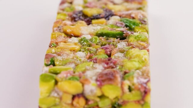 A delicious pistachio bar, with a  mix of grains, fruits, and nuts. Slider shot. Depth of field, selective focus. Organic and wholesome foods, granola bar, candies, sweet treats, snacks, concepts. 4k