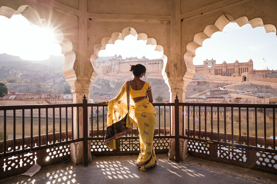 Indian woman with yellow saree standing inside an arched pavilion, Amer Fort, Rajasthan, India