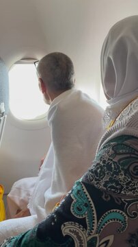 An elderly man in ihram and an elderly woman are flying in a plane for Umrah in Mecca. Flying over the Miqat.
