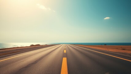 Naklejka premium Asphalt road stretching towards a tranquil ocean horizon under a serene sky
