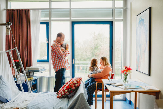 Family of 4 in hospital room with newborn baby - Powered by Adobe