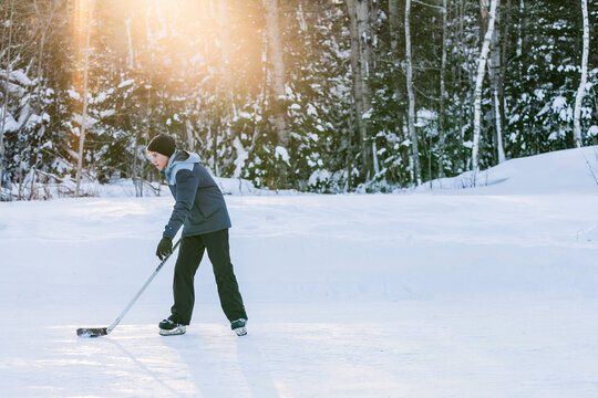 Teenager playing ice hockey on outdoor rink