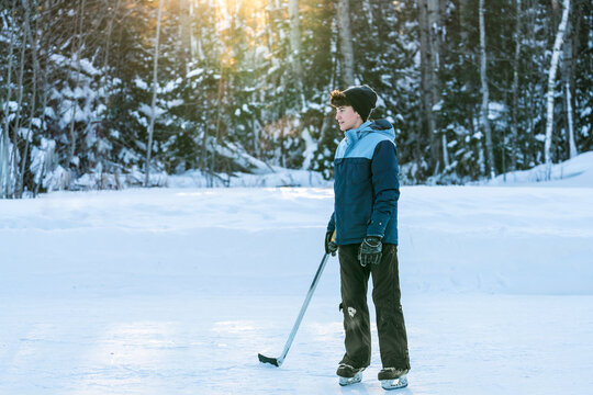 Teenager playing hockey on outdoor rink in winter