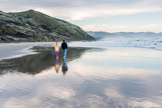 Father and daughter walking on beach in New Zealand