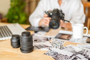 Professional photographer reviewing photos and holding camera in home office, surrounded by equipment and technology