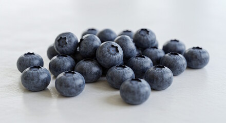 "A handful of ripe blueberries scattered naturally across a white background, each berry sharp and detailed."