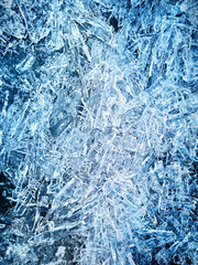 Abstract background made of surface of crashed freezed or frozen ice texture made from lake water at cold arctic winter season of blue transparent colour with frost cracks used as natural decoration