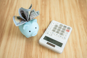 A blue piggy bank with calculator on wooden table.