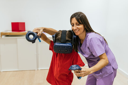 Optometrist helping boy wearing virtual reality glasses during consultation