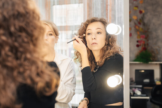 A professional makeup artist conducts a master class on professional development, observing the student's work.