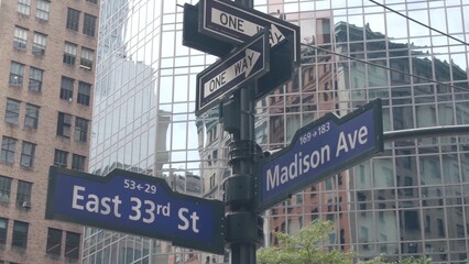 New York City crossroad, Manhattan corner, Madison avenue, street intersection road sign. Midtown central district highrise architecture, United States. One way arrow roadsign, skyscrapers. Low angle.