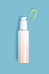 White mockup bottle of face cream with smear applied on blue isolated background. Concept of beauty products, moisturizing and skin care.