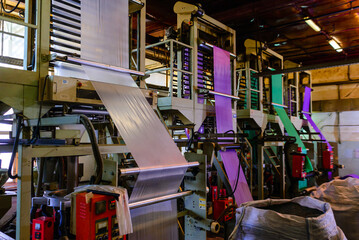A large roll of laminating film set against the backdrop of a bustling industrial environment