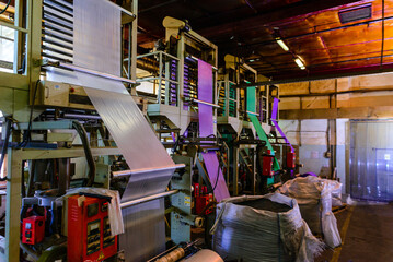 A large roll of laminating film set against the backdrop of a bustling industrial environment