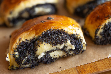 Closeup of freshly baked homemade poppy seed rolls with chocolate topping on parchment paper. Indulgent bakery treats and concerns about unhealthy, fattening diet. Blurred bokeh background.