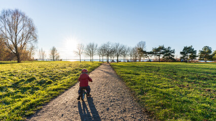 Obraz premium A young boy driving his bike at the Cospudener Lake in Leipzig in late autumn