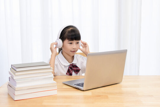 Chinese little girl attending online classes at home - Powered by Adobe