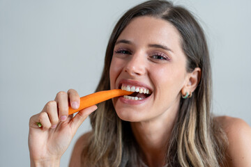 Smiling woman enjoying a carrot snack for a healthy lifestyle - Mindful eating habits with healthy snacks