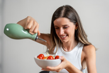 Woman pouring olive oil over a fresh salad for a healthy meal - mindful eating and vegetarian...
