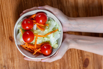 Hands holding a fresh salad bowl for healthy eating and wellness - balanced diet and healthy meal