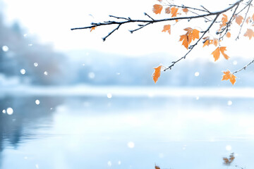 Snowy branch with autumn leaves over a calm lake.
