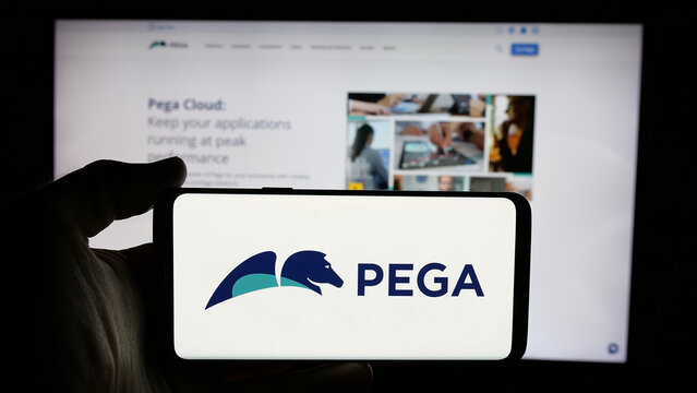 Stuttgart, Germany - 12-11-2024: Person holding cellphone with logo of American software company Pegasystems Inc. (Pega) on screen in front of webpage. Focus on phone display.