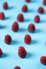 Red raspberries placed symmetrically on a light blue surface.