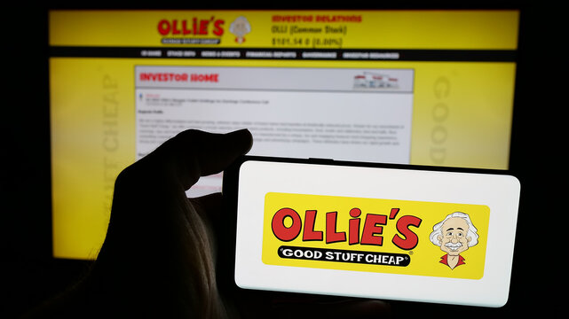 Stuttgart, Germany - 12-09-2024: Person holding mobile phone with logo of US company Ollie's Bargain Outlet Holdings Inc. on screen in front of web page. Focus on phone display.