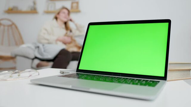 Laptop With Green Mock Up Screen On Table In Home Room With Woman and Her Dog