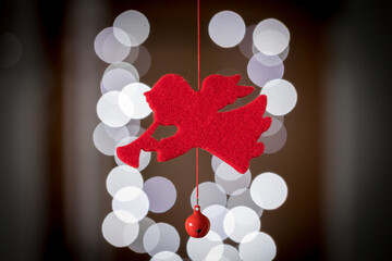 Decorazione natalizia rossa a forma di angelo con la tromba con luci sullo sfondo