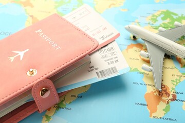 Passport with tickets and plane model on world map, closeup