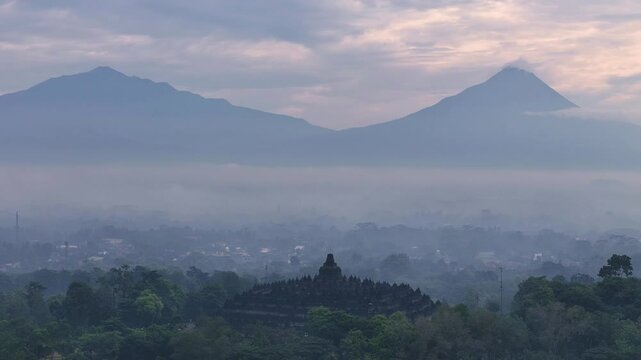 Ancient Borobudur temple with mountains in background, aerial early morning view