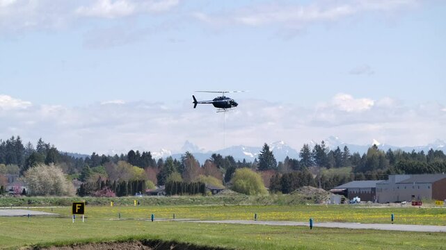Side View of a Helicopter Hovering Above the Airfield, Sunny Day