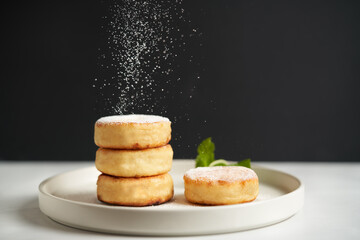 Syrniki or cottage cheese pancakes minimal concept with mint leaf on a white plate. Delicious syrniki pancakes topped with powdered sugar with copy space