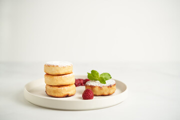Syrniki with cottage cheese and berries. Healthy breakfast concept, high protein on bright white background. 