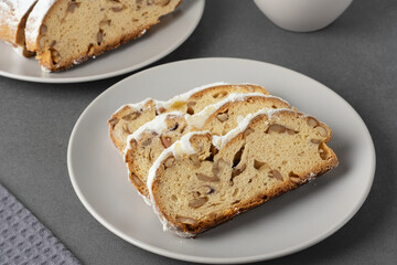 Delicious homemade stollen bread displayed on a plate with powdered sugar and chopped nuts in festive setting