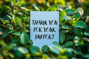 Thank you for your support message written on white card on a bush
