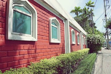 Painted red brick wall with windows along the sidewalk