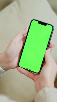 Mobile Phone With Green Mock Up Screen In Female Hands Close Up. Vertical Video