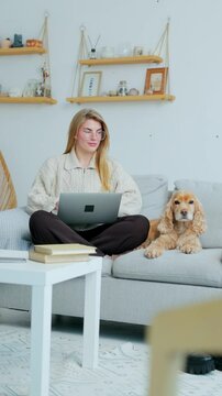 Vertical Video. Young Freelance Woman Working on Laptop Sitting at Home with Her Dog