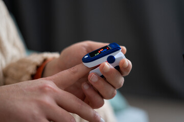 Pulse oximeter on male hand measuring oxygen saturation at home. Medical device with monitoring ox...