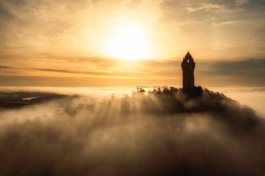 Wallace Monument in Stirlingshire, Scotland, emerging through morning fog at sunrise